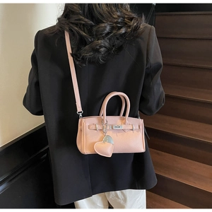 Pink mini crossbody bag featuring pebbled texture, silver lock, and heart charm on a model