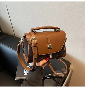 Detail view of brown vintage crossbody bag with contrast stitching and metallic round lock