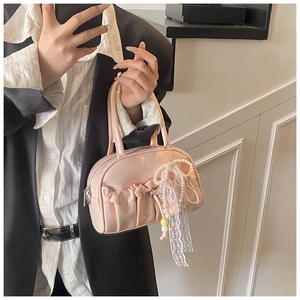 Detail of light pink pleated bowling bag with delicate pearl and lace bow charm detail
