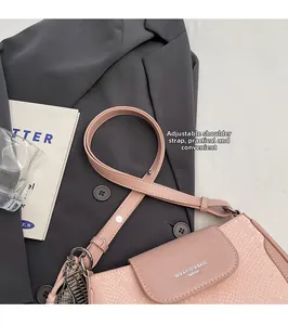 Detail of pink snake-texture crossbody bag with adjustable strap on grey blazer