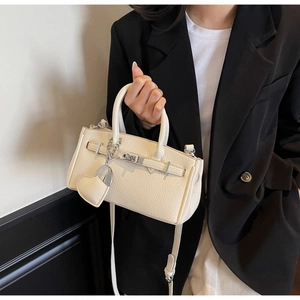 Close-up of creamy white lychee grain leather bag with silver lock and heart charm