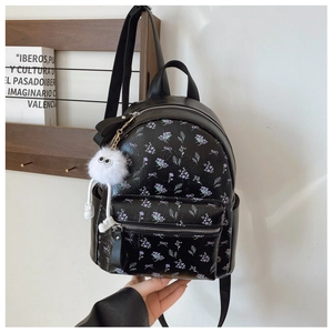 Détail du sac à dos en cuir noir imprimé floral avec charm monstre et fermetures argentées