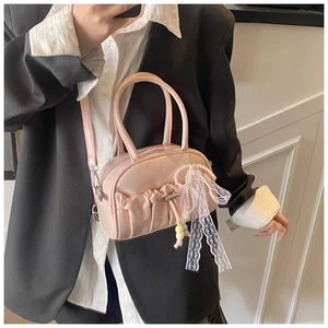 Pink glossy bowling bag featuring pleated design and pearl lace charms detail view
