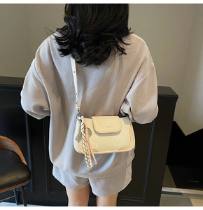 Detail of cream white textured faux leather shoulder bag with floral embossed pattern
