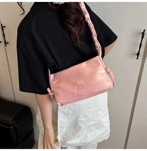 Dettaglio borsa tote in morbida pelle rosa con fiocchi decorativi e tracolla arricciata
