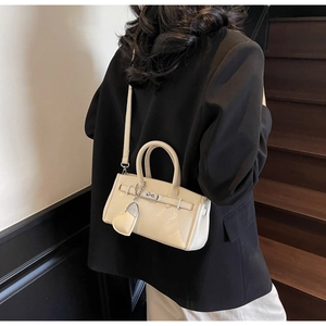 Detail of lychee textured leather mini bag in cream with silver lock and heart charm