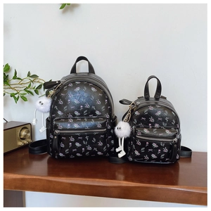 Détail de sacs à dos noirs à fleurs en deux tailles avec charms en peluche sur bois
