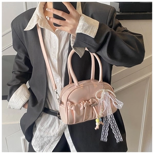 Detail of pink pleated mini bowling bag with pearl and lace bow charm accessories
