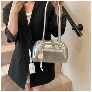 Detail der silbernen Metallic-Schultertasche mit kreativen Anhängern auf schwarzem Anzug
