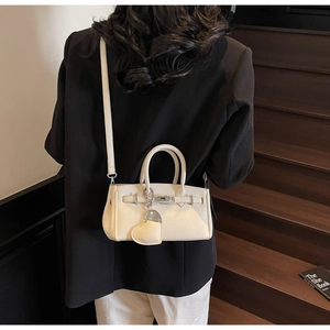 Rear view of model wearing white lychee leather handbag with heart pendant on stairs