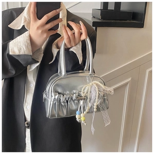 Detail of silver metallic pleated bowling bag with pearl and lace bow charm