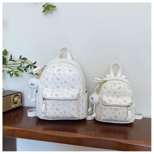 Détail de sacs à dos à fleurs en deux tailles avec nœuds roses et porte-clés peluche