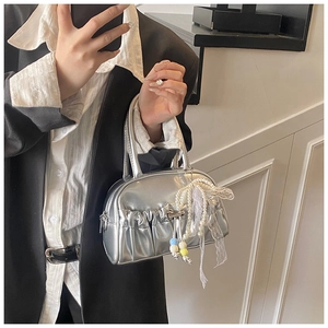 Detail of silver metallic pleated bowling bag with pearl lace charm on dark blazer
