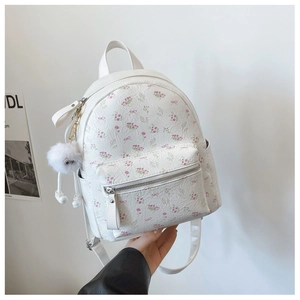 Détail d'un mini sac à dos blanc à motifs floraux avec porte-clés monstre en peluche