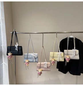 Detail of minimalist envelope underarm bags in five colors with lace bows and bear charms