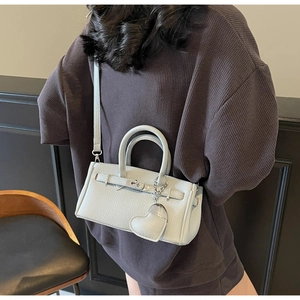 Rear view of a model carrying a light blue lychee pattern handbag with a heart charm