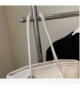 Detail of cream tote bag with silver metal ring buckle and reinforced stitching