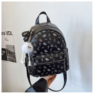 Détail d'un mini sac à dos en cuir noir avec motifs floraux violets et charm peluche