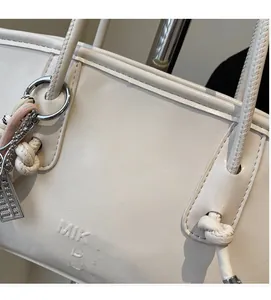Detail of off-white PU leather tote bag with lychee texture and creative charms
