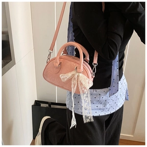 Detailed macro view of pink patent leather shell bag with embossed texture and lace bow