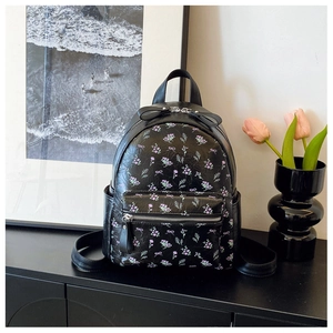 Gros plan du motif floral et des nœuds sur le sac à dos en similicuir noir