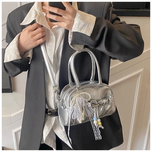 Detail of silver metallic pleated bowling bag with pearl charms and lace decoration