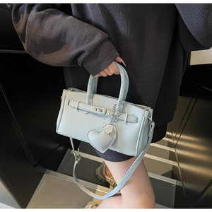 Detail of light blue pebbled leather handbag featuring silver twist lock and heart charm