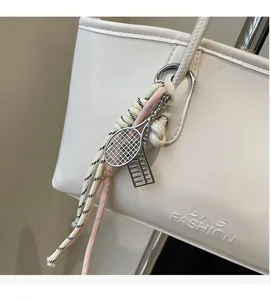Close-up of white leather tote bag with silver tennis racket charm and woven cord detail
