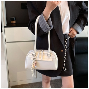 Nahaufnahme der cremefarbenen PU-Leder-Schultertasche mit Anhängern im Retro-Minimalismus