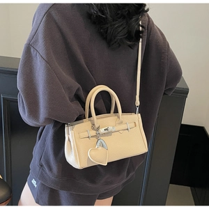 Detailed view of beige pebbled leather mini handbag with silver hardware and heart charm