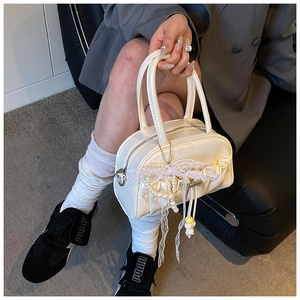 Detail of cream pleated bowling bag with delicate lace bow and pearl bead pendants