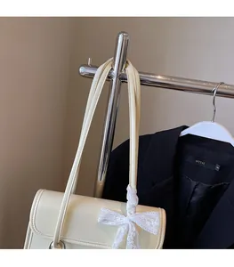Detail of cream shoulder bag featuring elegant lace bow and silver ring hardware