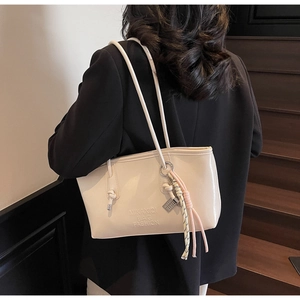Gros plan du sac fourre-tout crème avec logo MIKAXIQI et pendentif en corde tressée