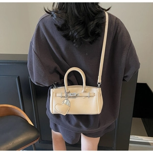 Model wearing a beige lychee pattern handbag with metal lock and heart charm