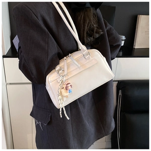 Detail der weißen minimalistischen Kunstleder-Schultertasche mit Anhänger am Model