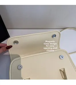 Close-up of dual magnetic snap closure on cream underarm bag with faux leather texture