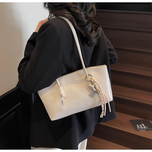 Détail d'un cabas crème avec logo en relief et accessoire élégant en corde tressée