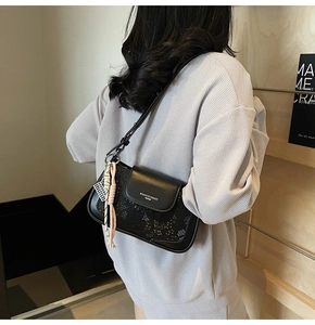 Close-up of black crossbody bag with hollow-out texture and leather strap detail