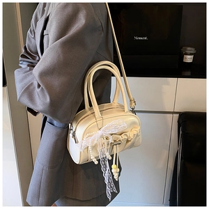 Detailed side view of pleated cream bowling bag with lace trim and pearl chain strap
