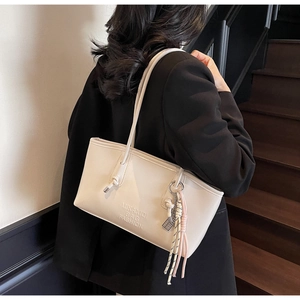 Détail du sac fourre-tout crème avec lettrage MIKANIQI et anse à nœuds élégante