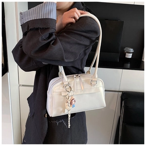 Detail der weißen Boston Bag aus PU-Leder mit Perlmuttglanz und süßem Puppenanhänger