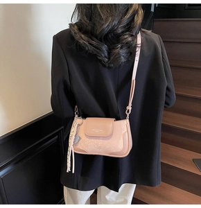 Detail of light pink shoulder bag with snakeskin texture and decorative tassel on strap
