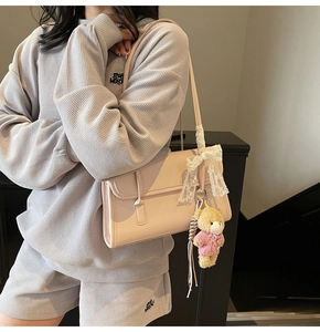 Detail of pink faux leather shoulder bag with lace bow and cute teddy bear pendant charm