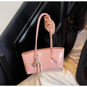 Détail du sac à main rose brillant avec pendentif raquette de tennis et pompon tressé
