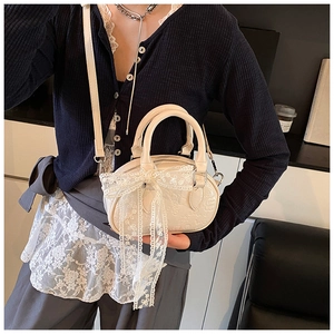 Detail of cream lace bow and embossed floral texture on elegant mini bowling bag