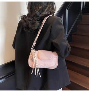 Detail of light pink crossbody bag featuring snake skin texture and tassel charm