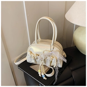 Close-up of cream white pleated Boston bag with elegant pearl bow and lace charms
