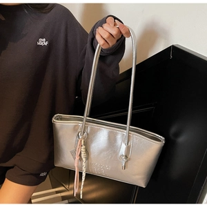 Detail of silver metallic tote bag with embossed logo and decorative pink rope charm