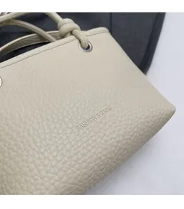 Close-up of beige lychee grain faux leather handbag with embossed FASHION & BAGS logo
