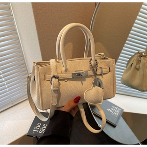 Detail of cream lychee leather texture with twist lock and heart-shaped bag charm